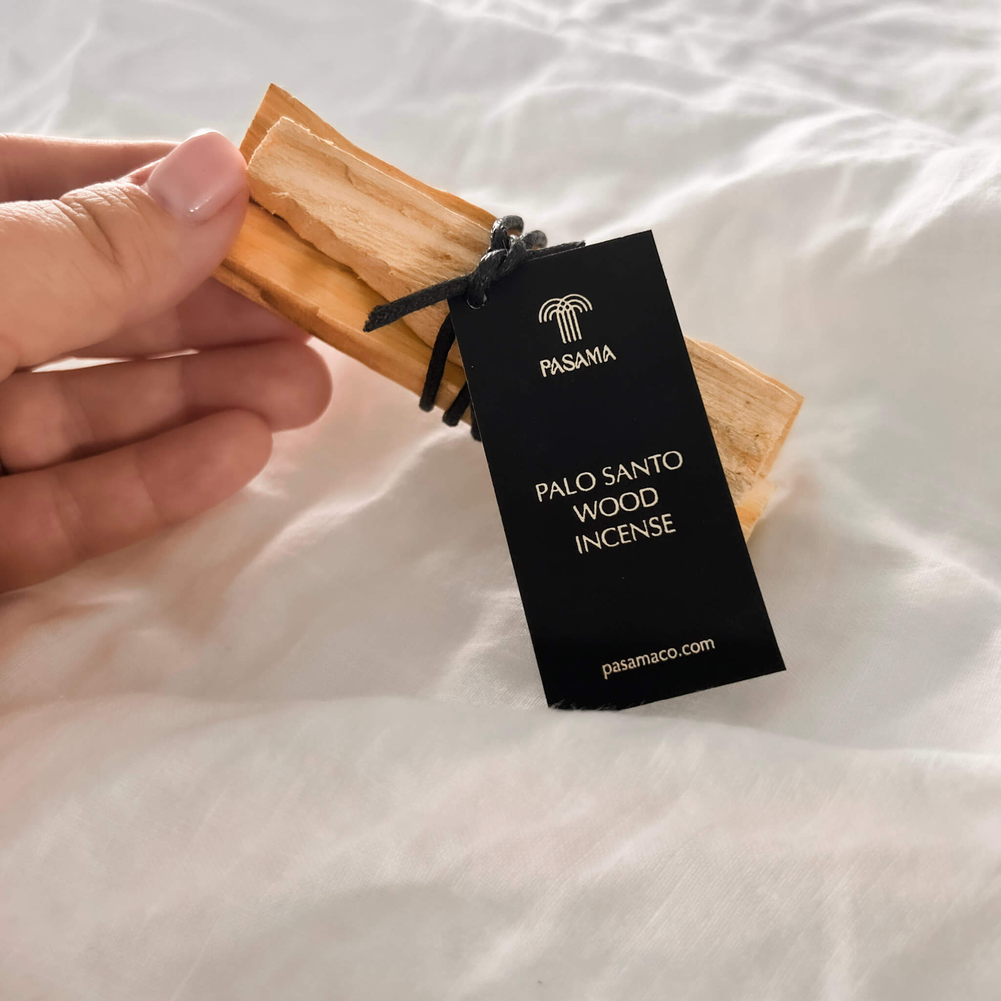 hand holding a bundle of 3 palo santo wood incense sage sticks