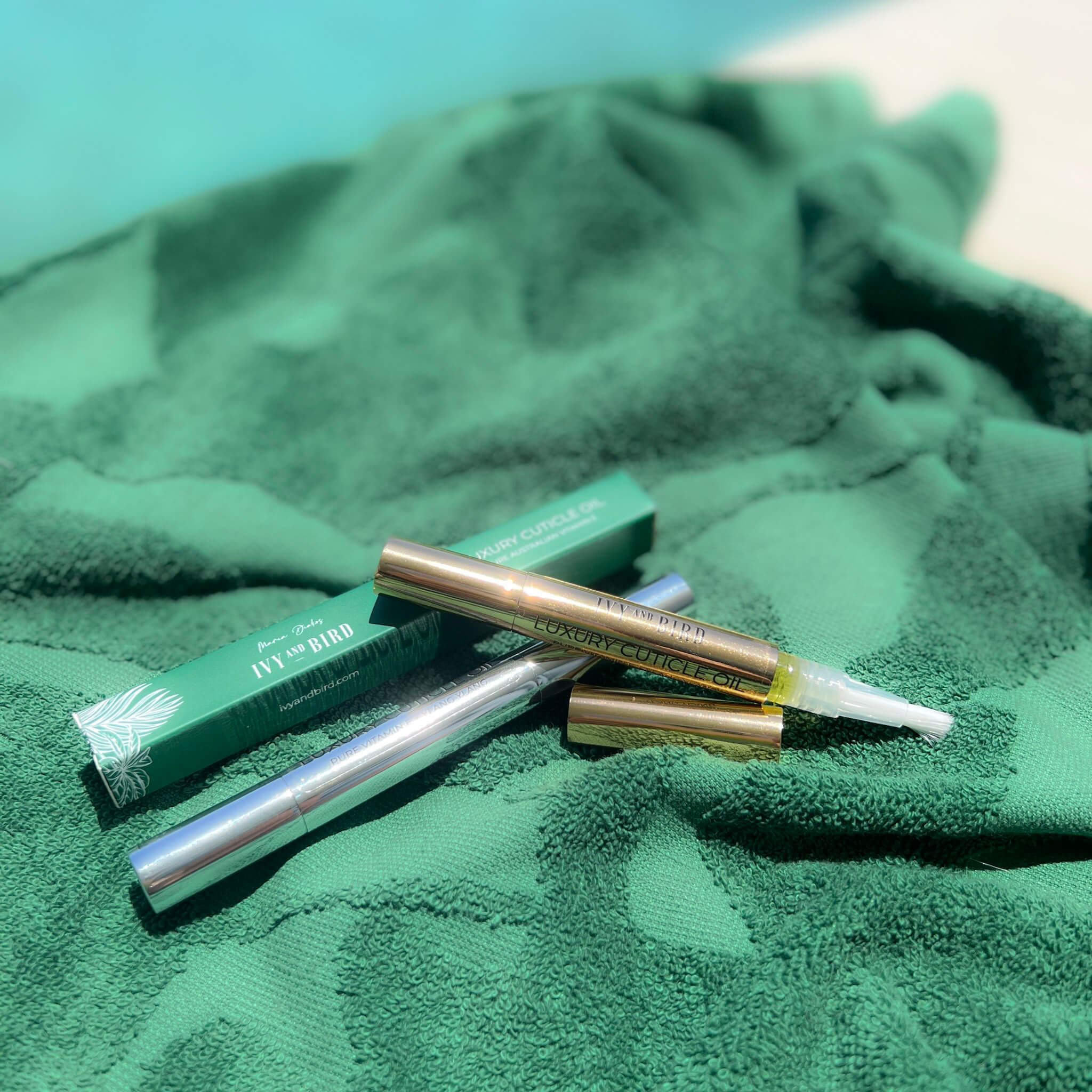 Cuticle oil pen on green beach towel by the pool